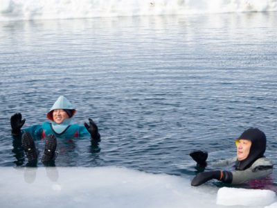 Two ladies floating in the water during a drift ice walk in Shiretoko, Hokkaido, Japan