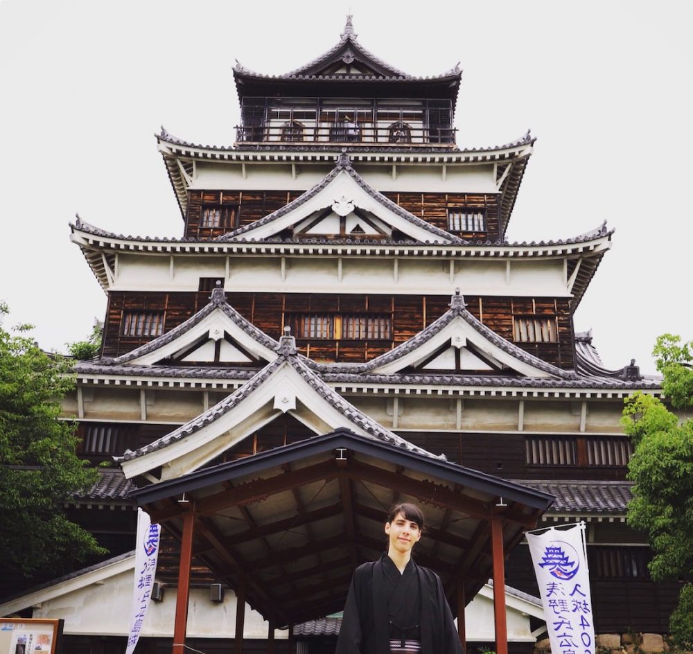 Man in kimono posing in front of Hiroshima Castle in Japan